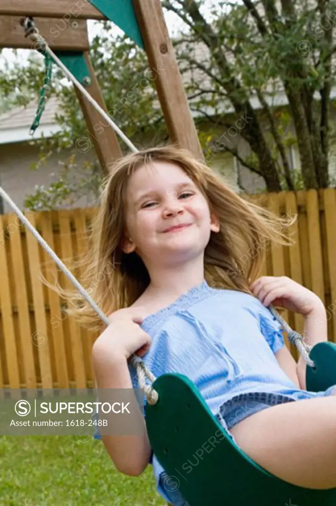 Portrait of a girl swinging on a rope swing