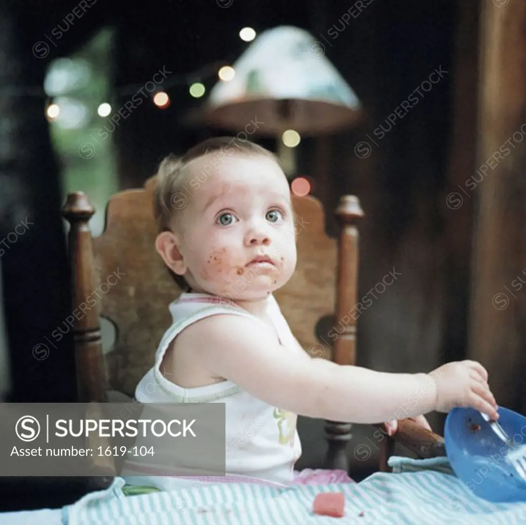 Close-up of a baby girl holding a bowl and a fork