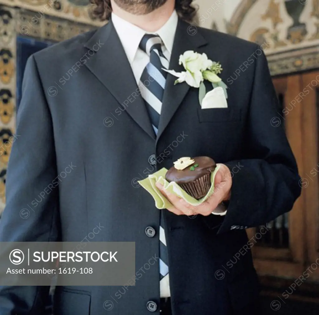 Mid section view of a man holding a cupcake