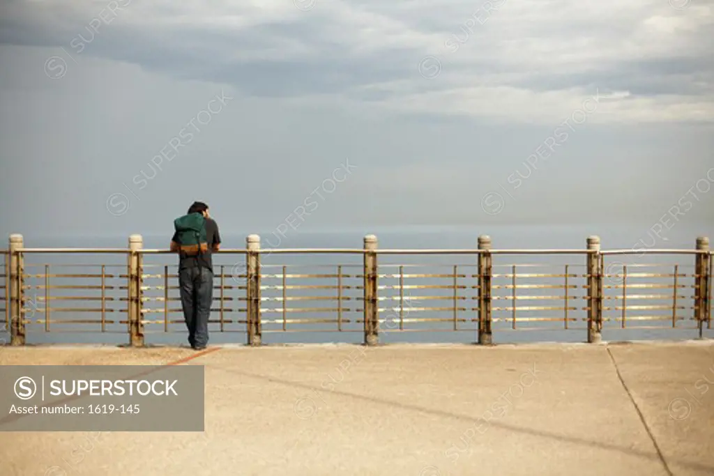 Man looking over railing at the seaside