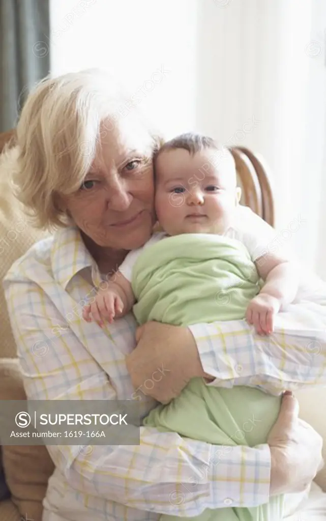 Portrait of grandmother embracing baby girl indoors