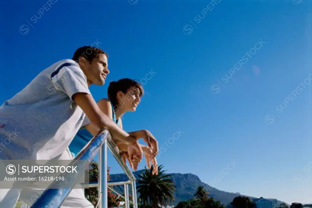 Low angle view of a young couple leaning against a railing