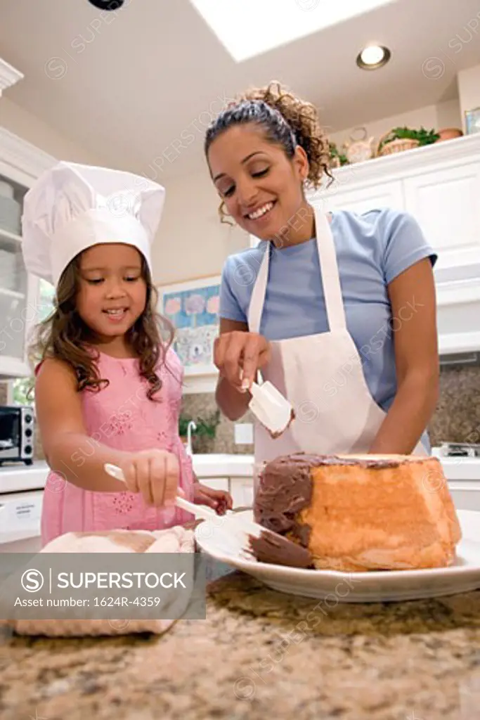 Mother and daughter icing a cake together