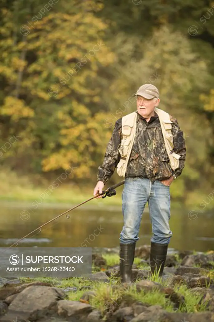Senior Man with Fishing Rod on Bank of River