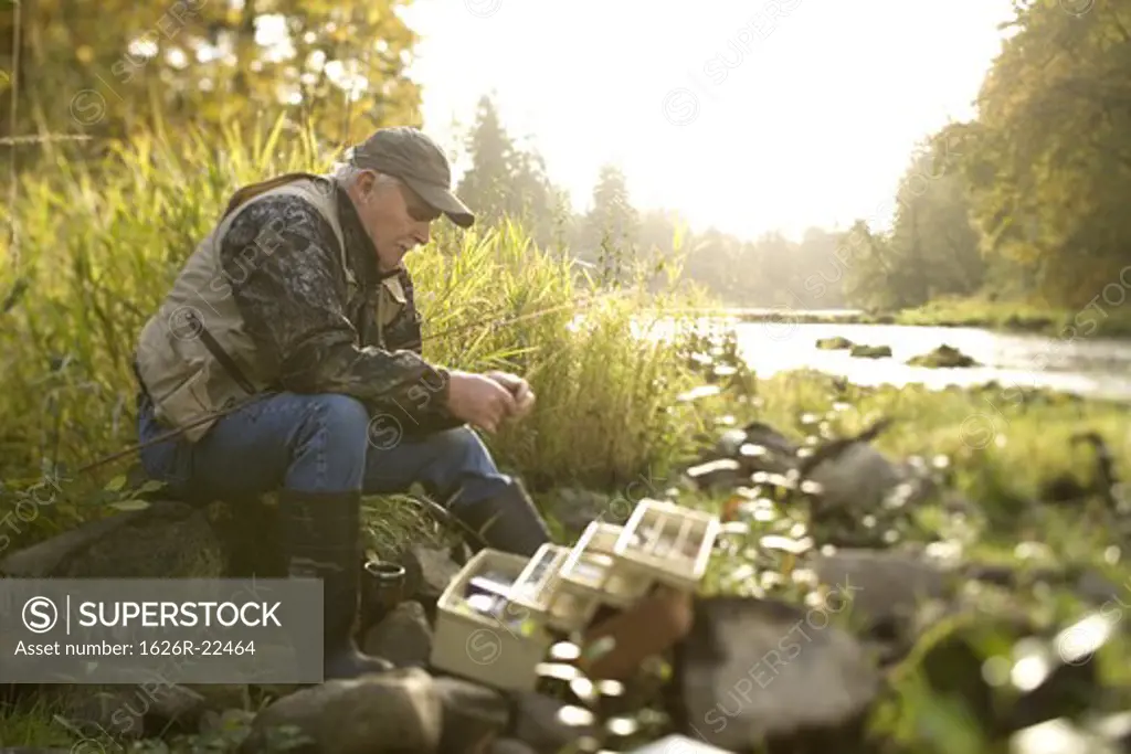 Senior Man Preparing Hook for Fishing on Bank of River