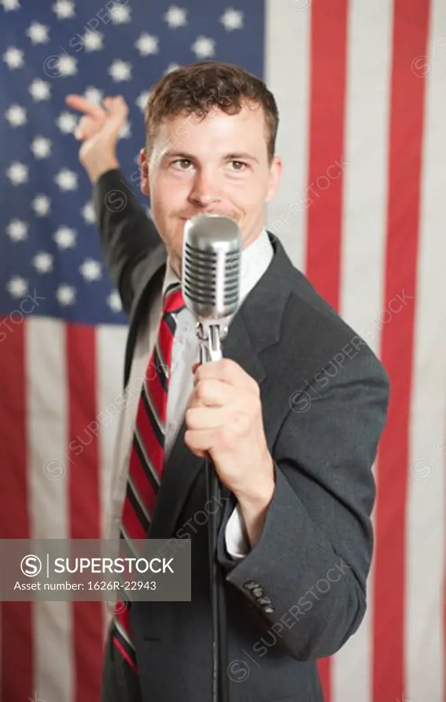 Young politician waving hand and speaking into microphone