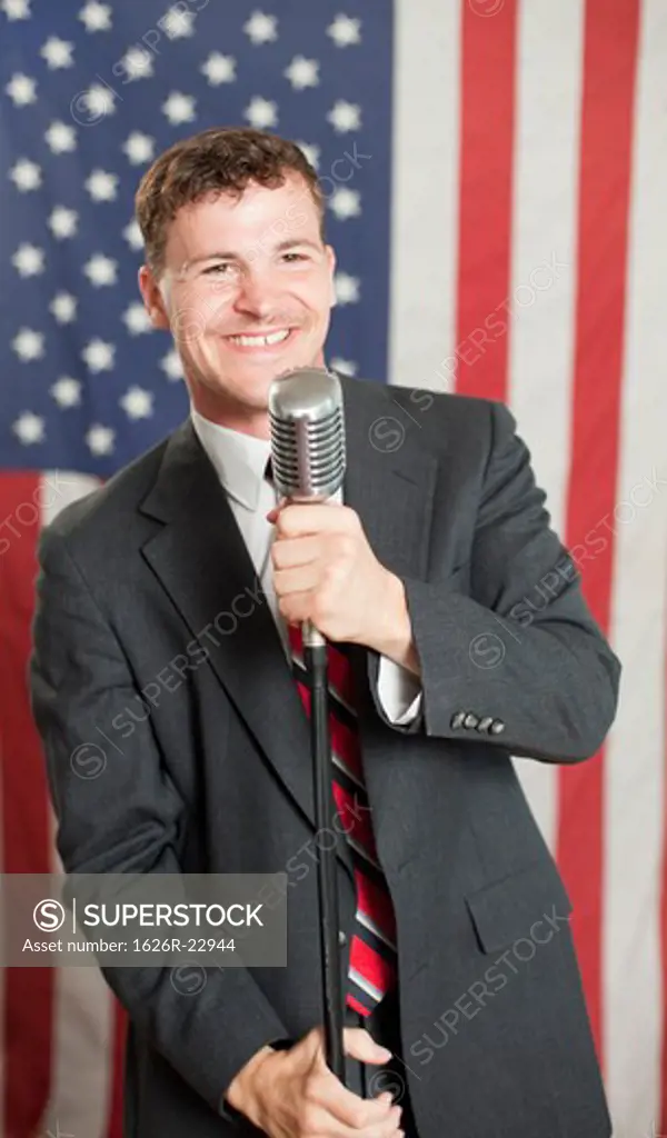 Young politician smiling and holding microphone stand