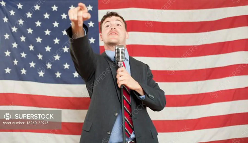 Young politician pointing and holding microphone stand