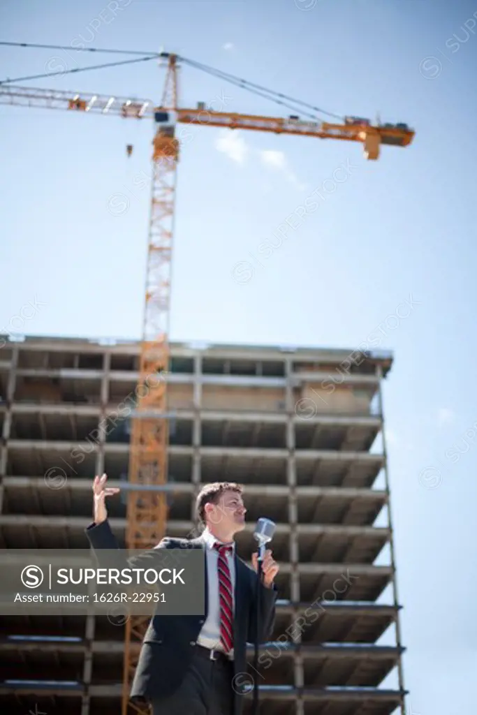 Young politician speaking and gesturing near construction site