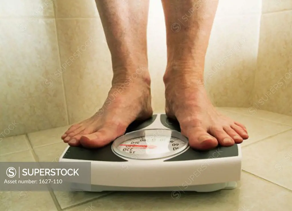 Low section view of a person standing on a weight scale