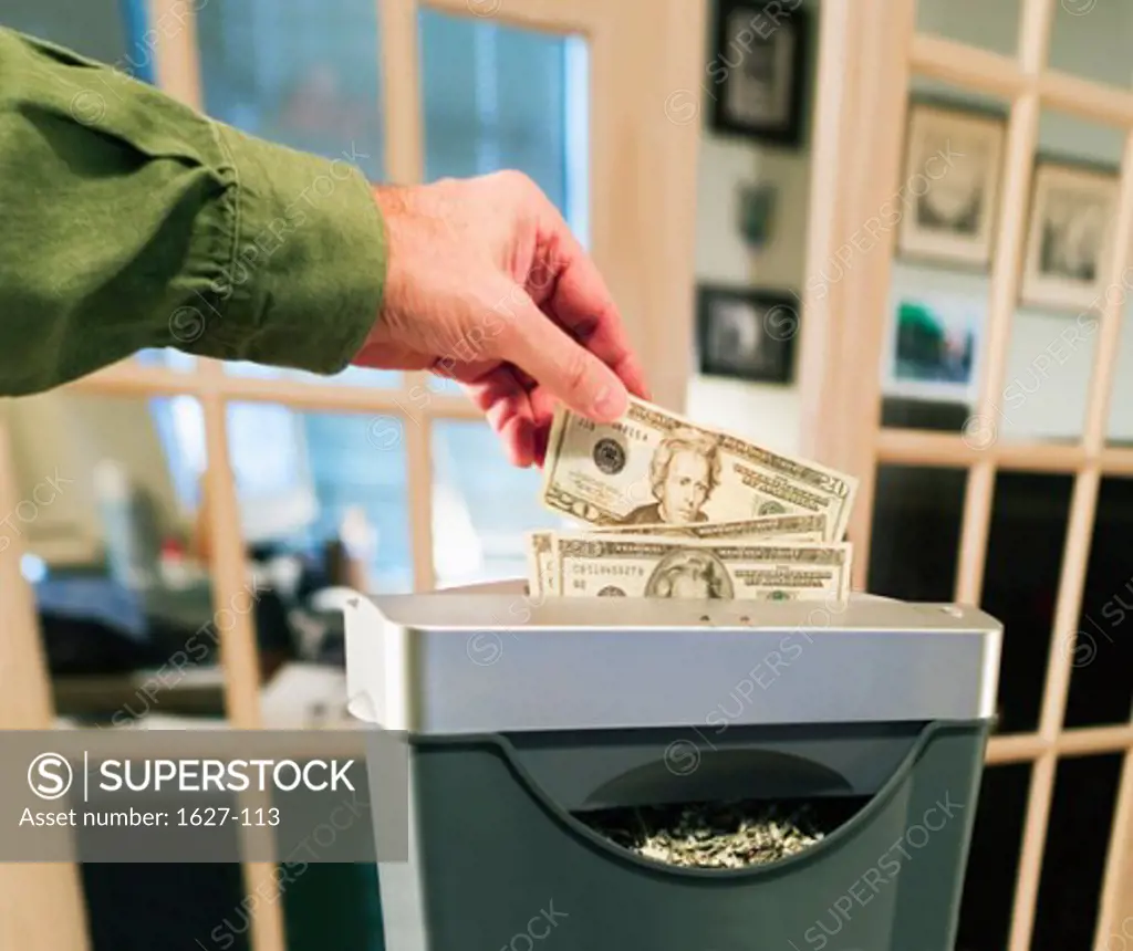 Close-up of a person's hands shredding paper currency