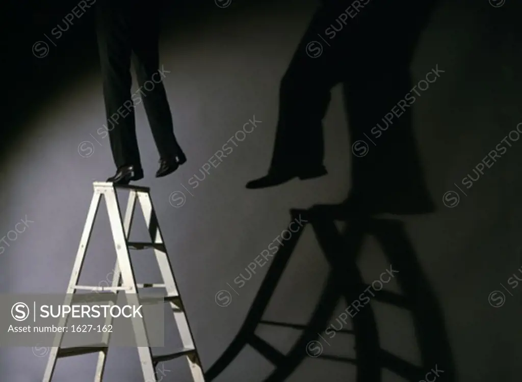 Low section view of a businessman falling from a step ladder