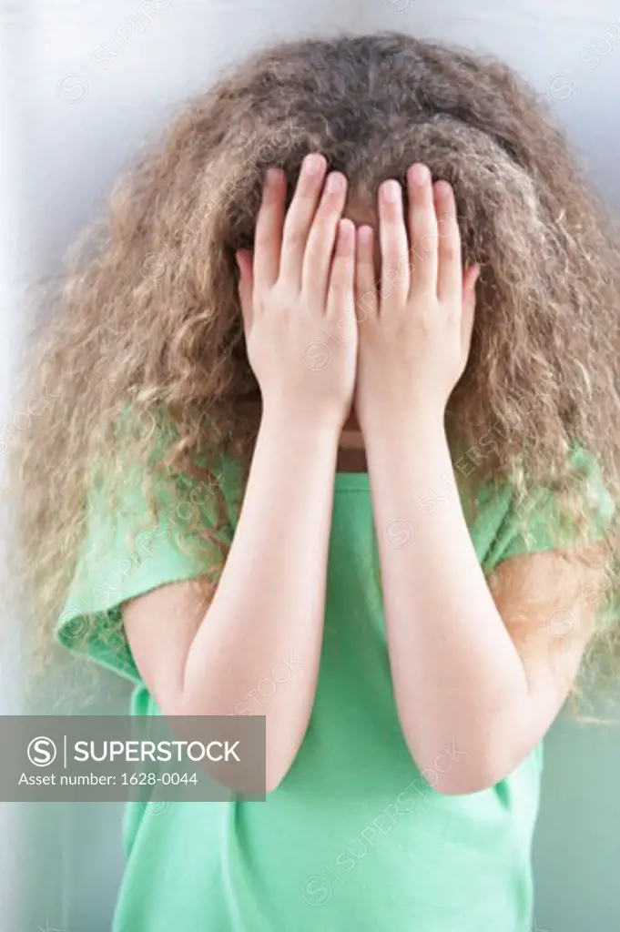 Close-up of a girl hiding her face with her hands