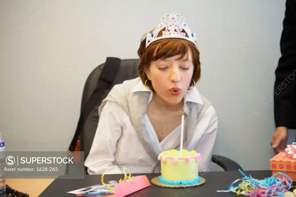 Close-up of a businesswoman blowing out a candle on her birthday cake