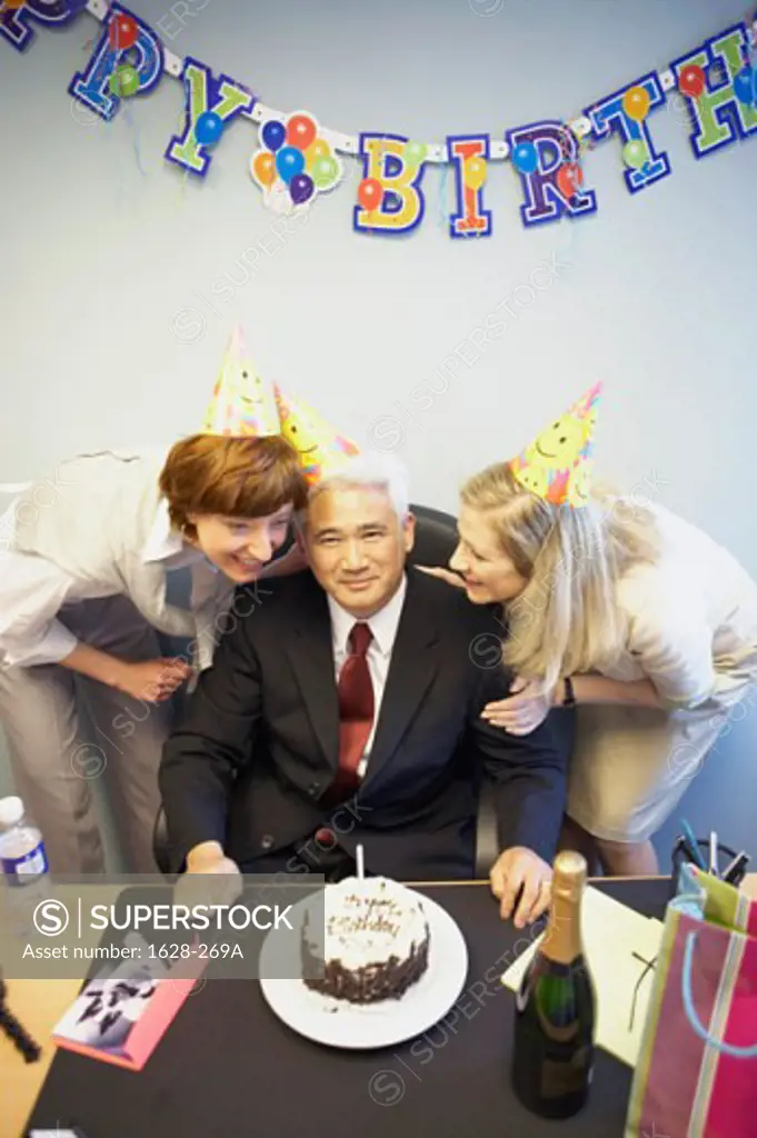 Portrait of a businessman celebrating his birthday with two businesswomen