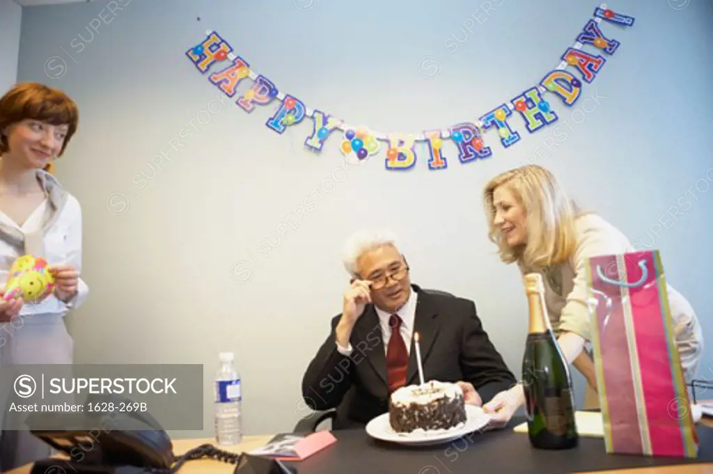 Businessman celebrating his birthday with two businesswomen