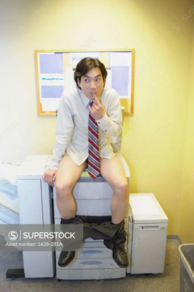 Businessman with his pants down sitting on a photocopier