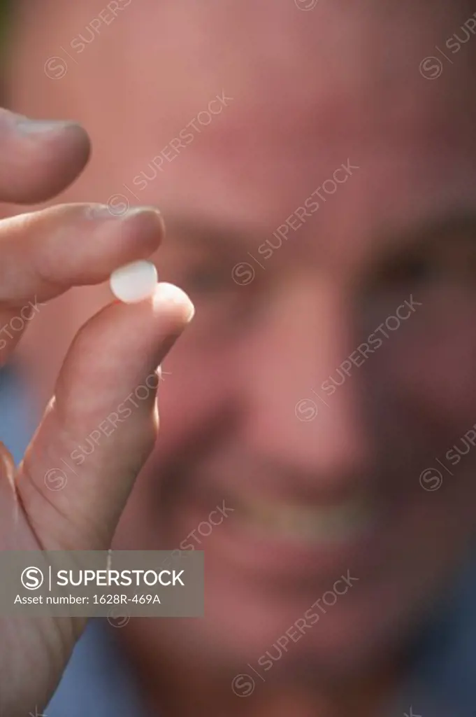 Close-up of a mature man showing a pill