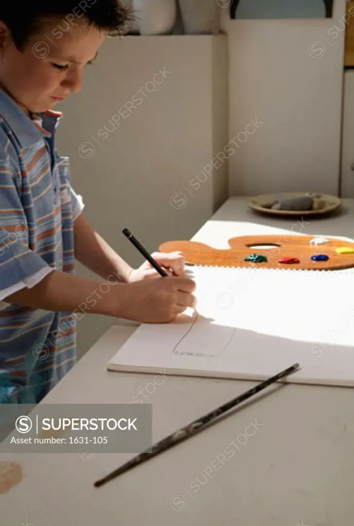Side profile of a boy drawing on a sketch pad