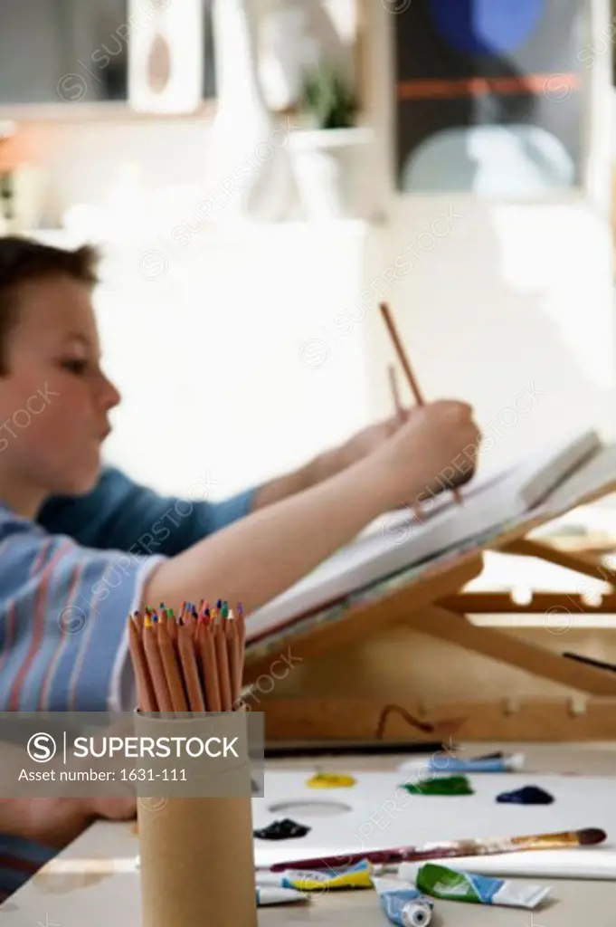 Side profile of a boy drawing on a sketch pad