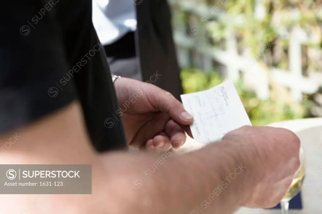 Mid section view of a man holding a bill