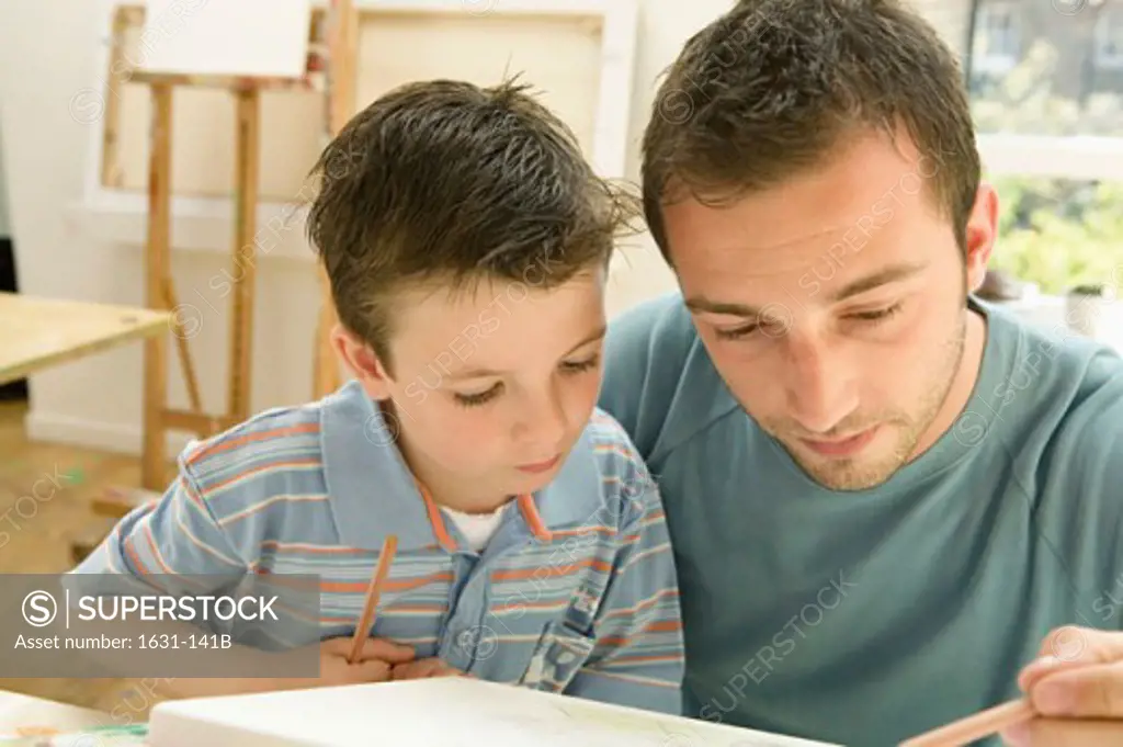 Close-up of a young man drawing with his son
