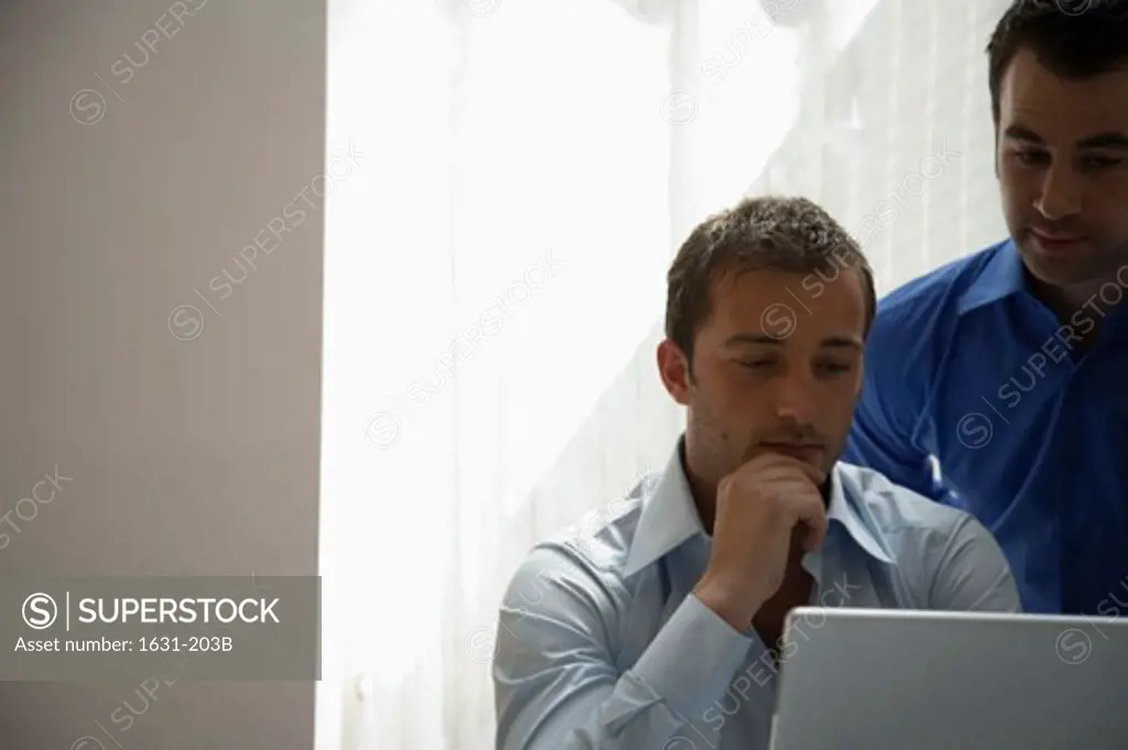 Close-up of two businessmen looking at a laptop