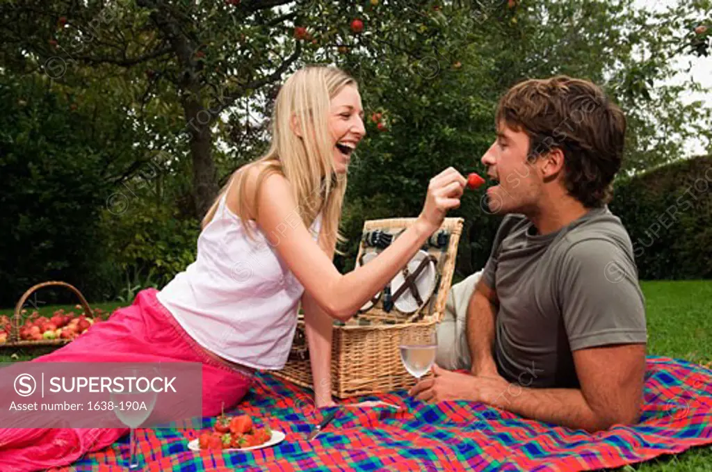 Side profile of a young woman feeding a strawberry to a young man