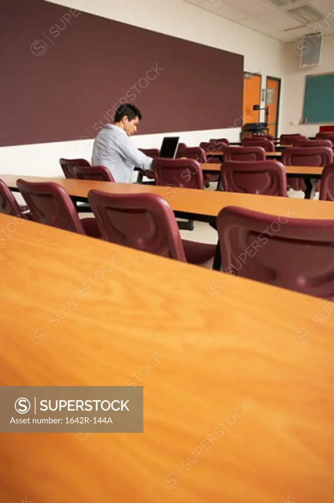 Side profile of a college student sitting in a lecture hall and using a laptop