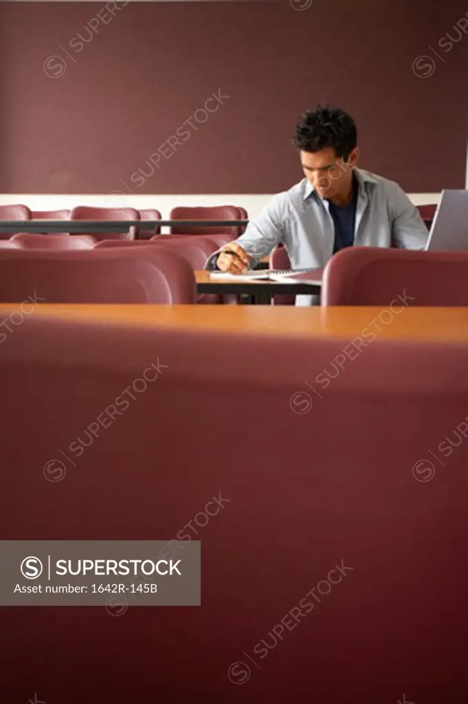 College student sitting in a lecture hall and studying