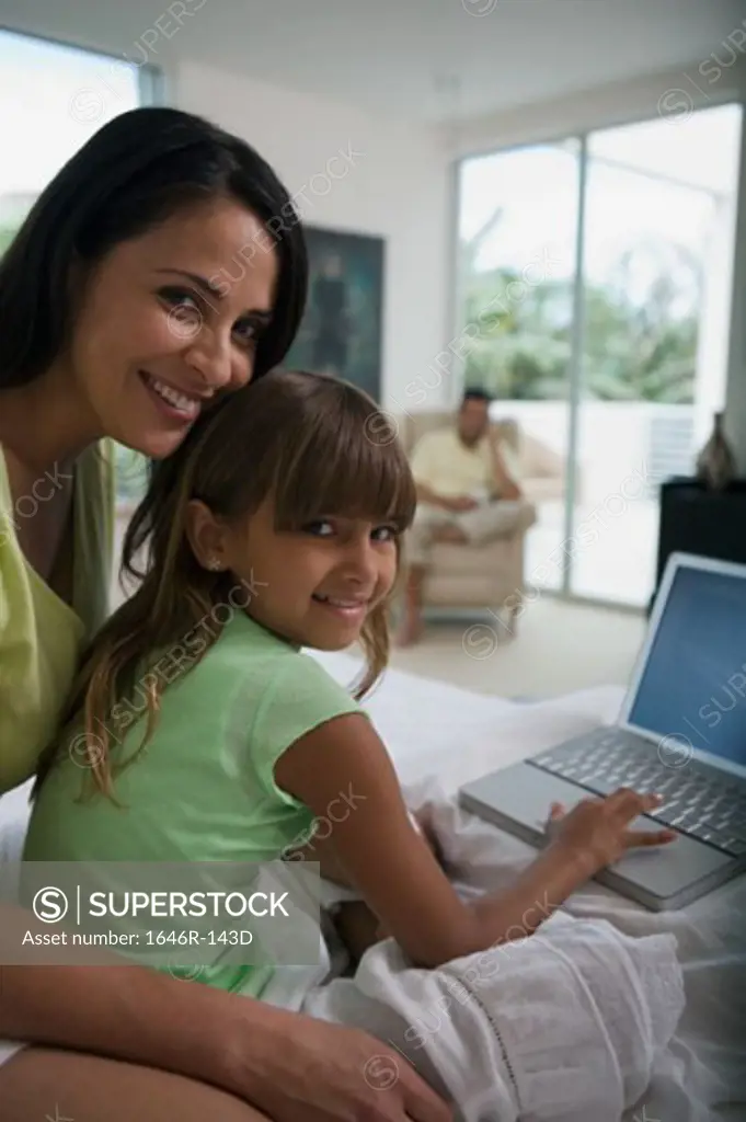 Girl using a laptop with her mother sitting behind her