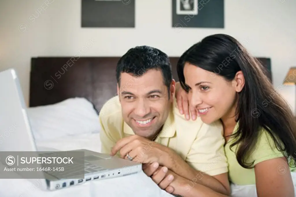 Close-up of a mature couple lying in front of a laptop and smiling