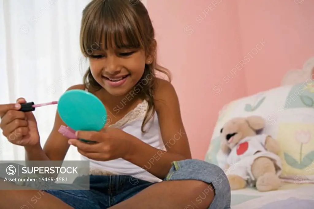 Close-up of a girl sitting in the bed and holding a hand mirror