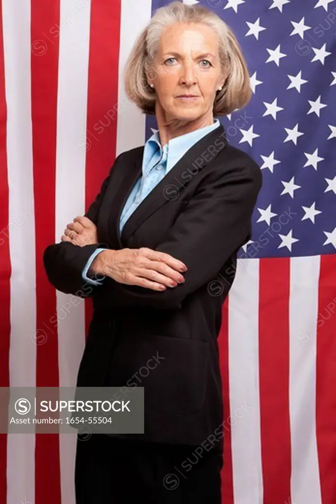 Studio. Senior businesswoman with arms folded standing infront of an American flag