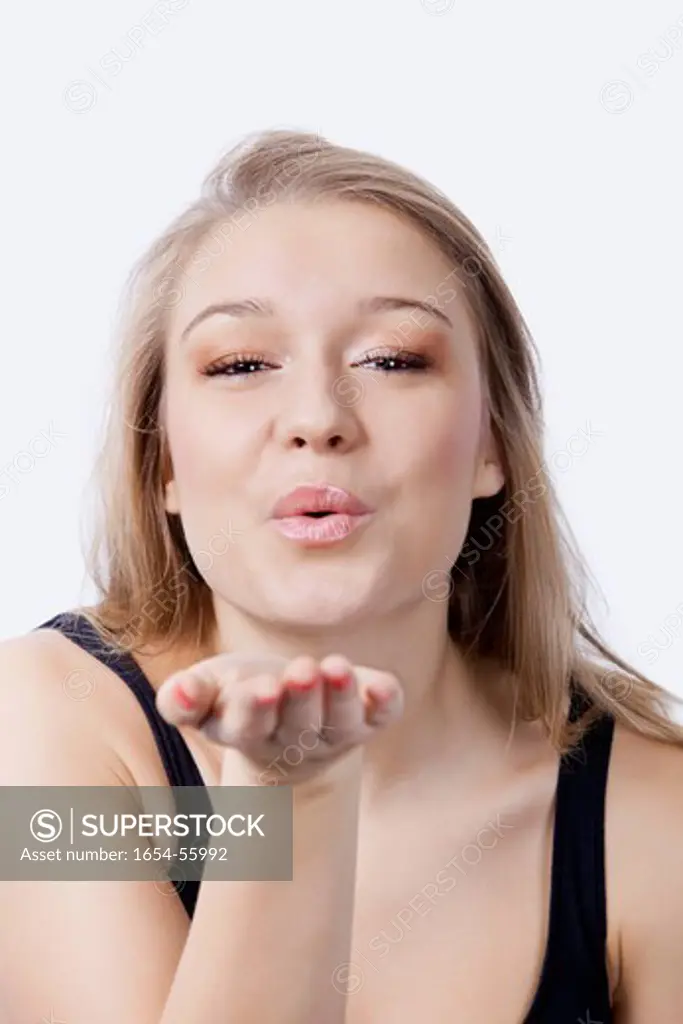 London, UK. Portrait of beautiful young woman blowing kiss against white background