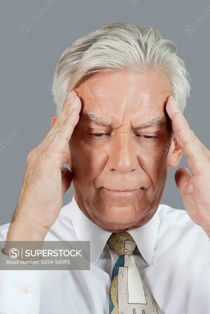 Palm Springs, California, USA. Close_up of senior businessman with headache over gray background