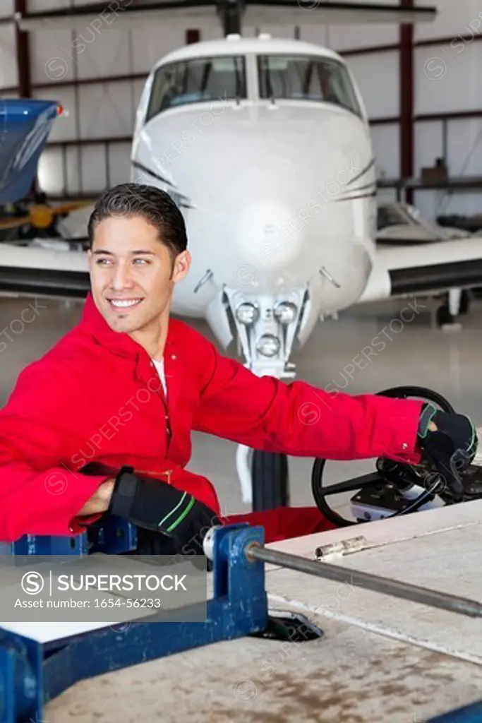 Palm Springs, California, USA. Happy aviation mechanic driving cart in airplane hangar