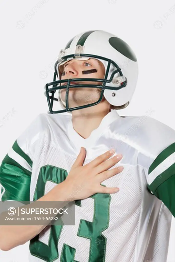 London, UK. Young man in football uniform with hand on chest against gray background