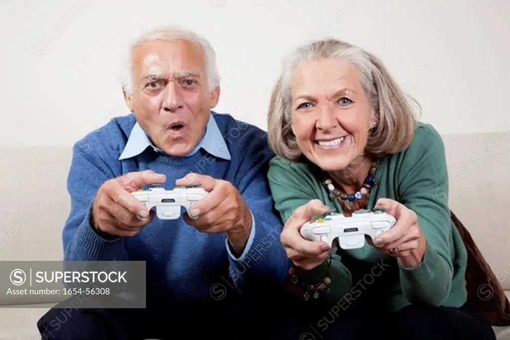 London, UK. Portrait of excited senior couple playing video game at home