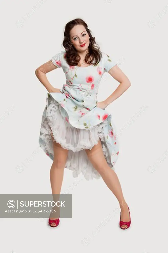 London, UK. Portrait of beautiful young woman in dress with hands on hips against white background