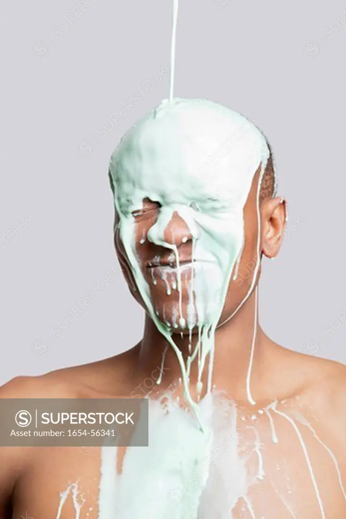 London, UK. Paint falling on shirtless young Hispanic man´s head against gray background
