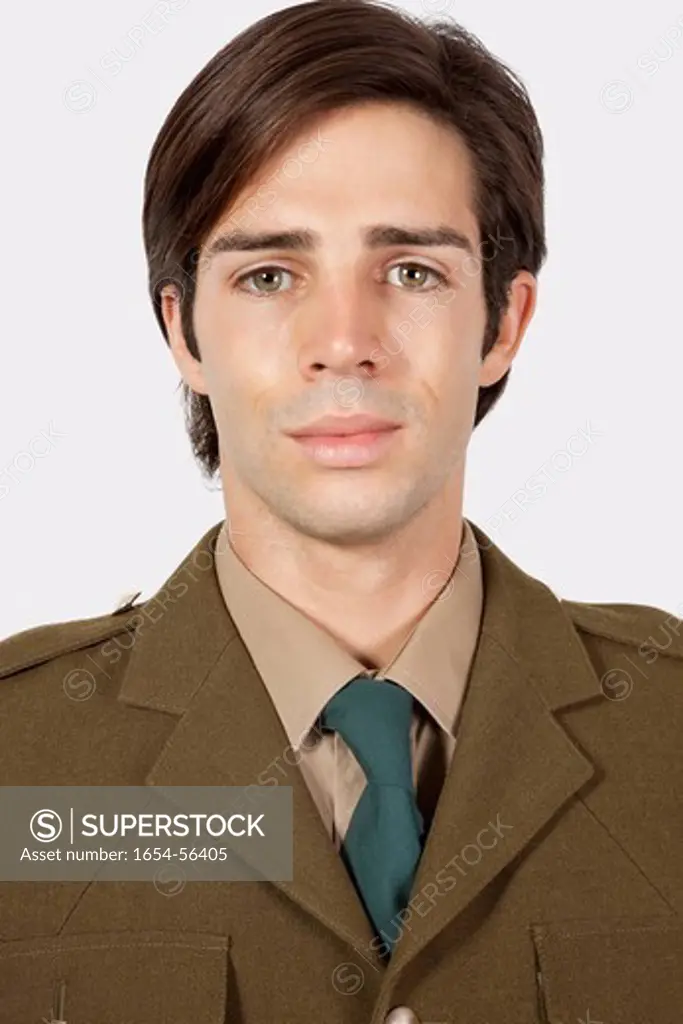 London, UK. Portrait of young man in military uniform against gray background
