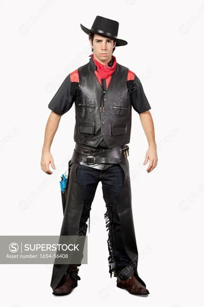 London, UK. Portrait of young cowboy in black leather vest standing against gray background