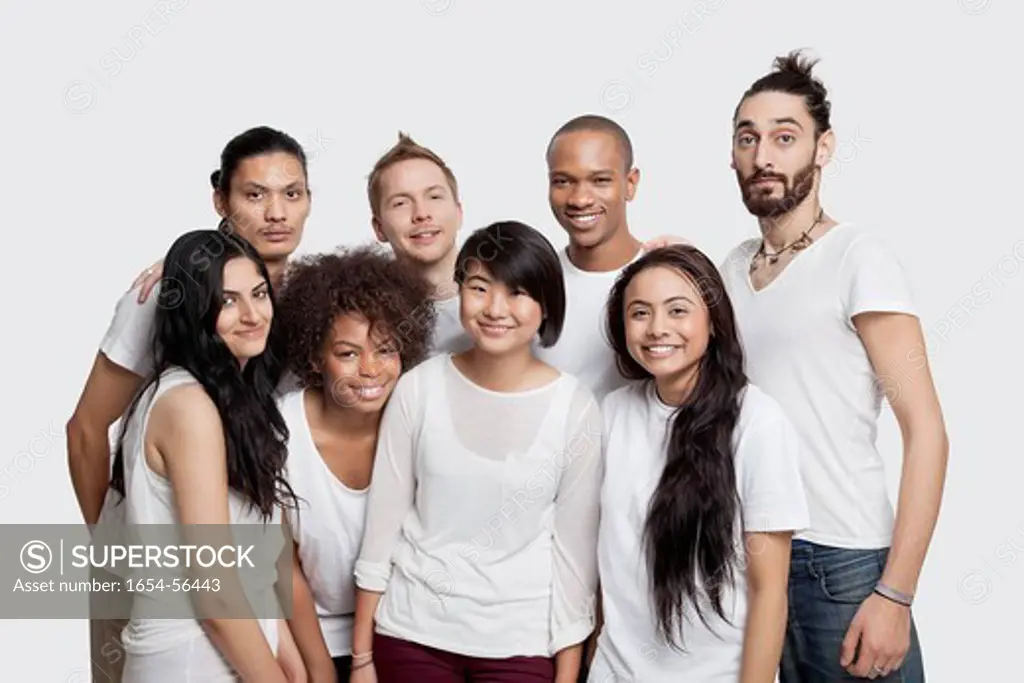 London, UK. Portrait of young multi_ethnic friends smiling together against white background