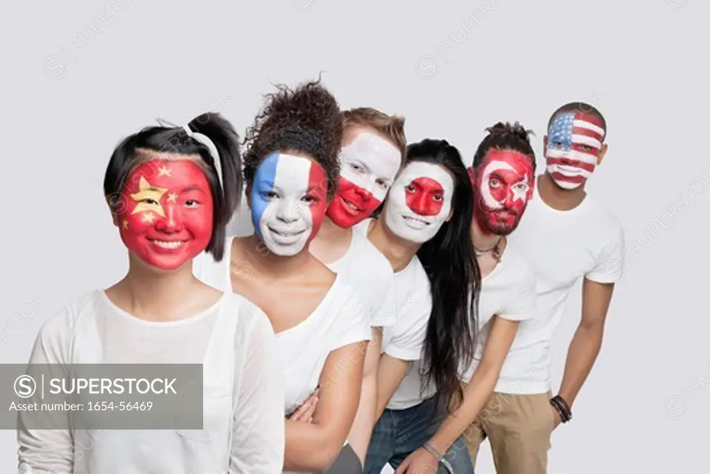 London, UK. Portrait of Multi_ethnic group of friends with various national flags painted on their faces standing in queue against white background
