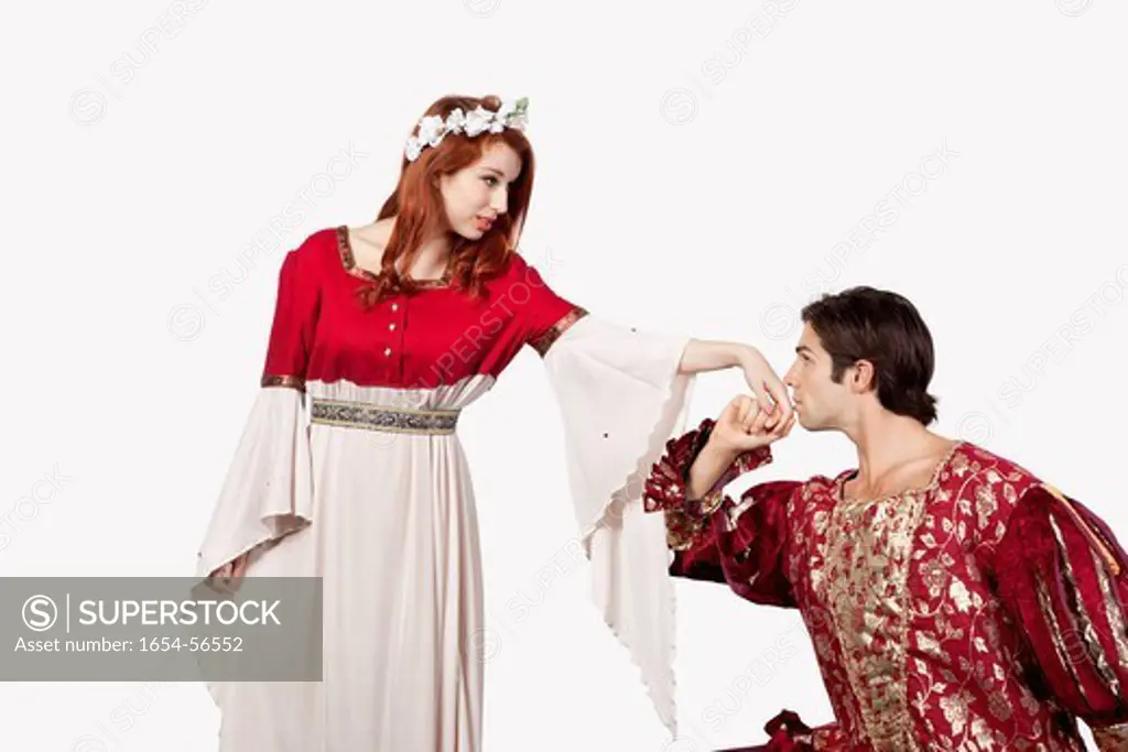 London, UK. Young man in old_fashioned costume kissing princess´s hand against gray background