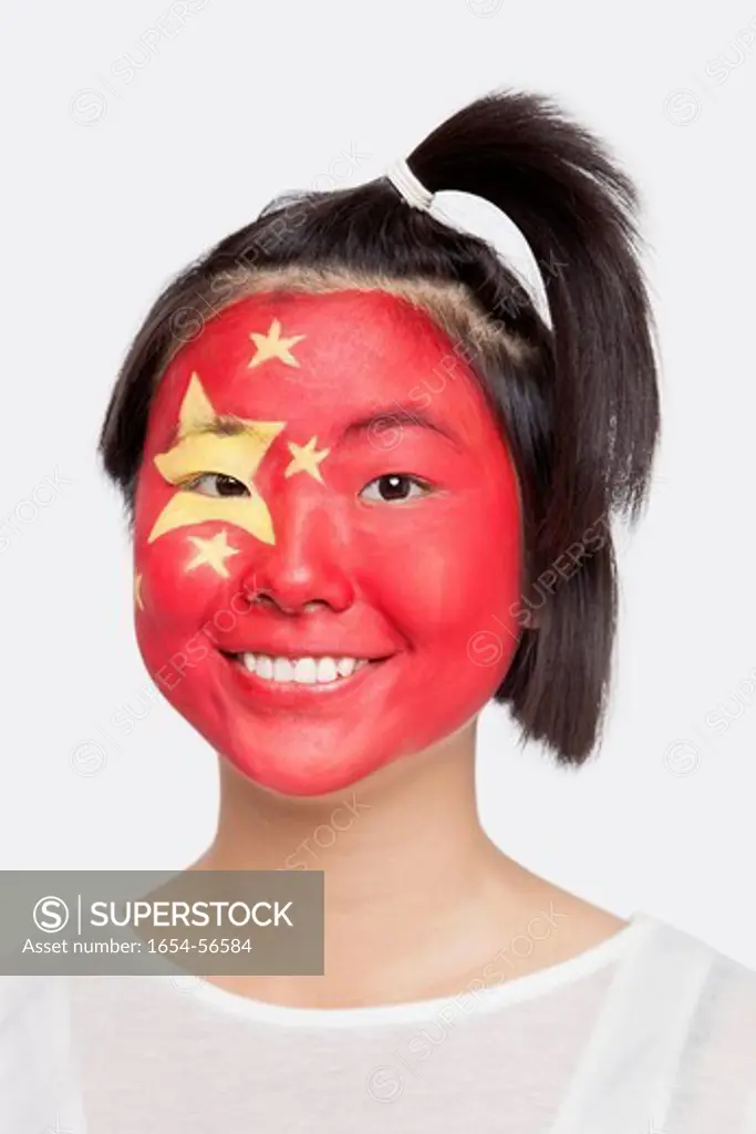 London, UK. Portrait of happy young Asian woman with Chinese flag painted on face against white background