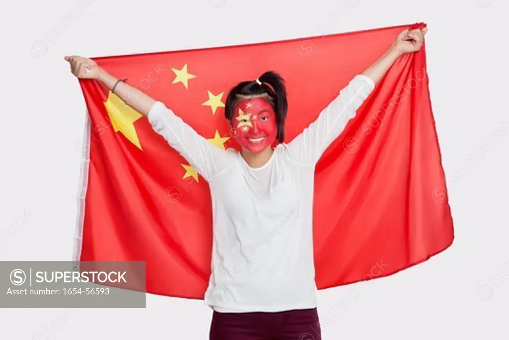 London, UK. Portrait of young Asian woman with Chinese flag and painted face against white background