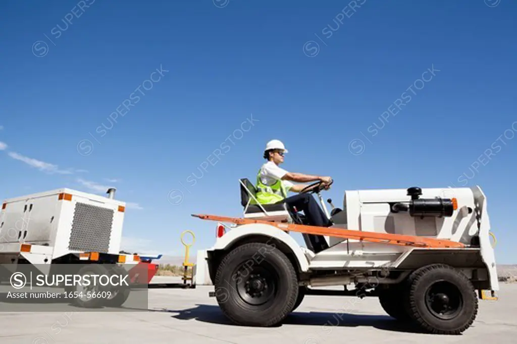 Palm Springs, California, USA. Young male ground crew driving truck at airport runway