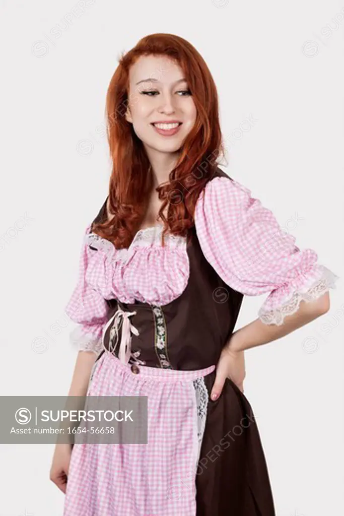 London, UK. Portrait of young woman in maid costume standing against gray background